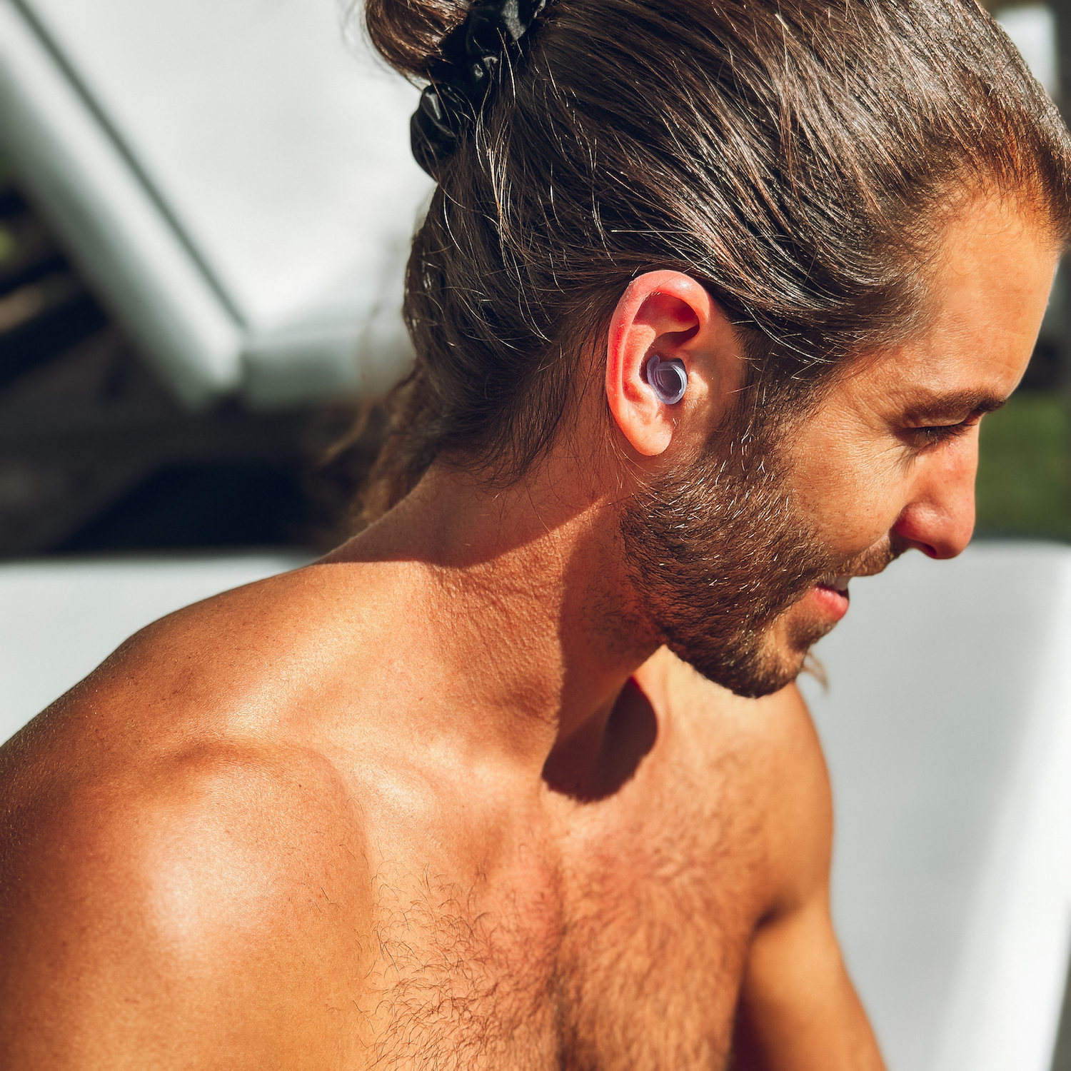 a man looking down with watersafe earplugs inserted