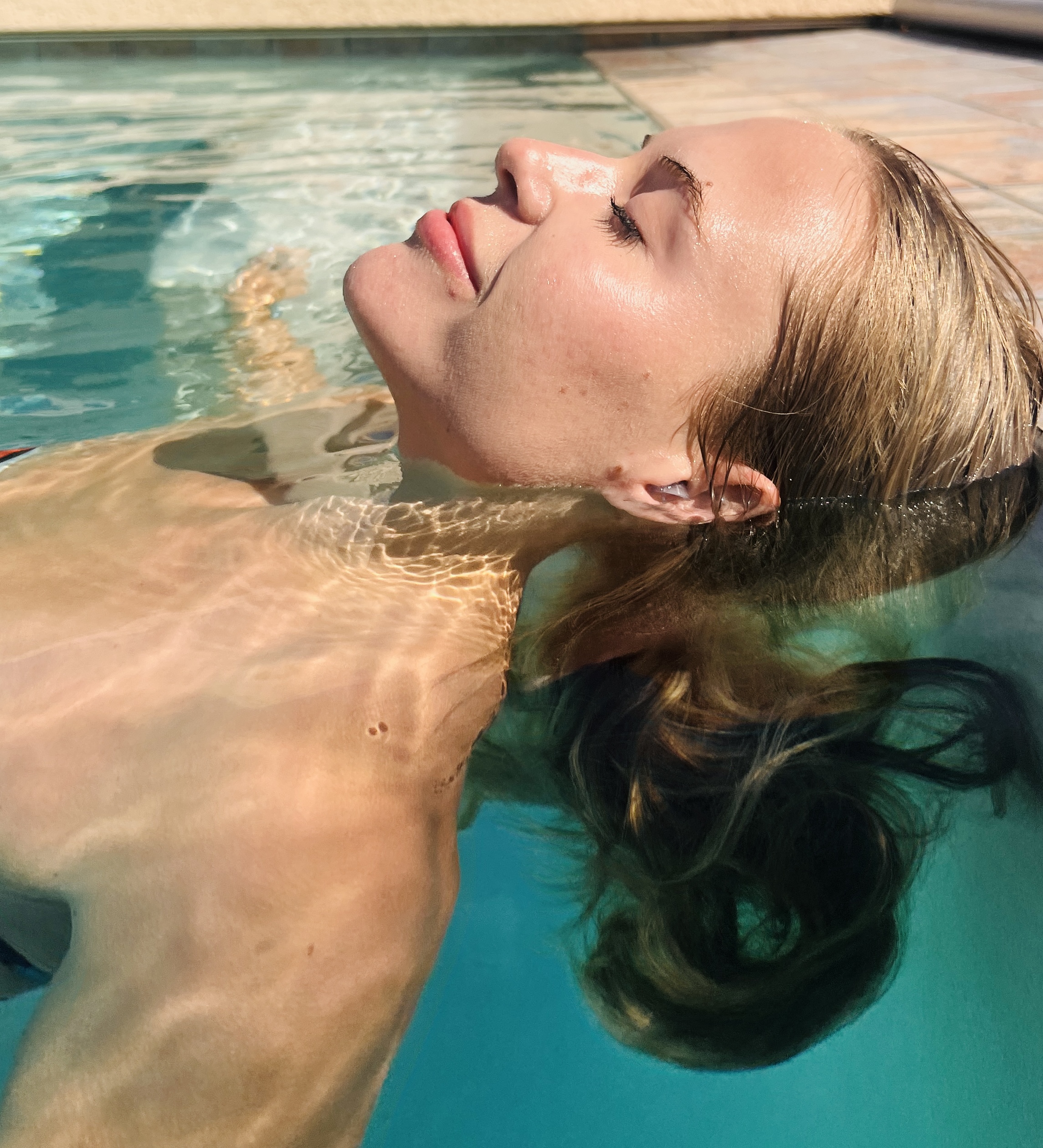 woman resting in the swimming pool with watersafe earplugs inserted